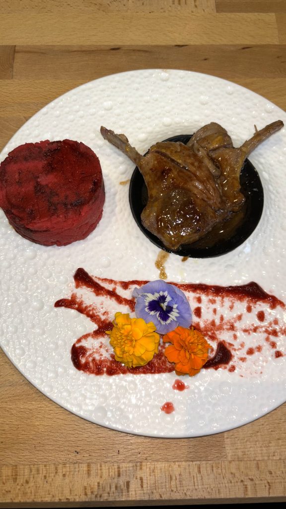 Carrello di agnello cotto a bassa temperatura con arancia, miele, curry, mango e rosmarino. Servito con purè di patate alla rapa rossa e fondo bruno